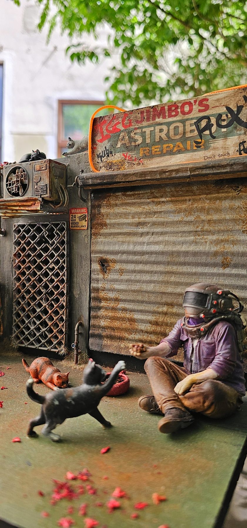 Masked figure offering food to cats in the Lunch Time diorama